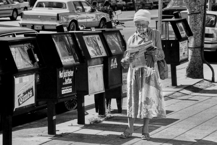 Femme lisant le journal dans la rue alone in la