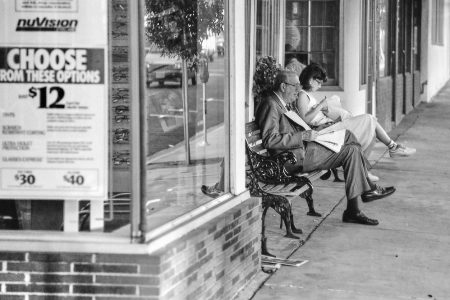 Un couple attend le bus assis sur un banc, alone in la