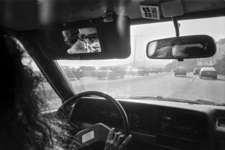 Une jeune femme au volant de sa voiture sur la PCH, alone in la