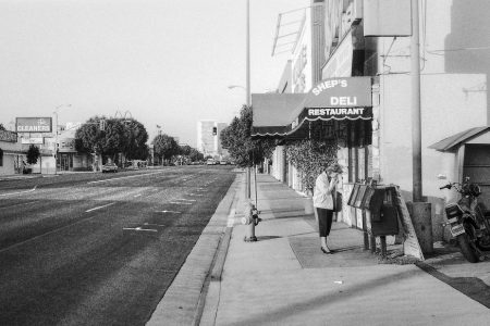 Une femme consulte la presse quotidienne, seule dans une rue de Los Angeles